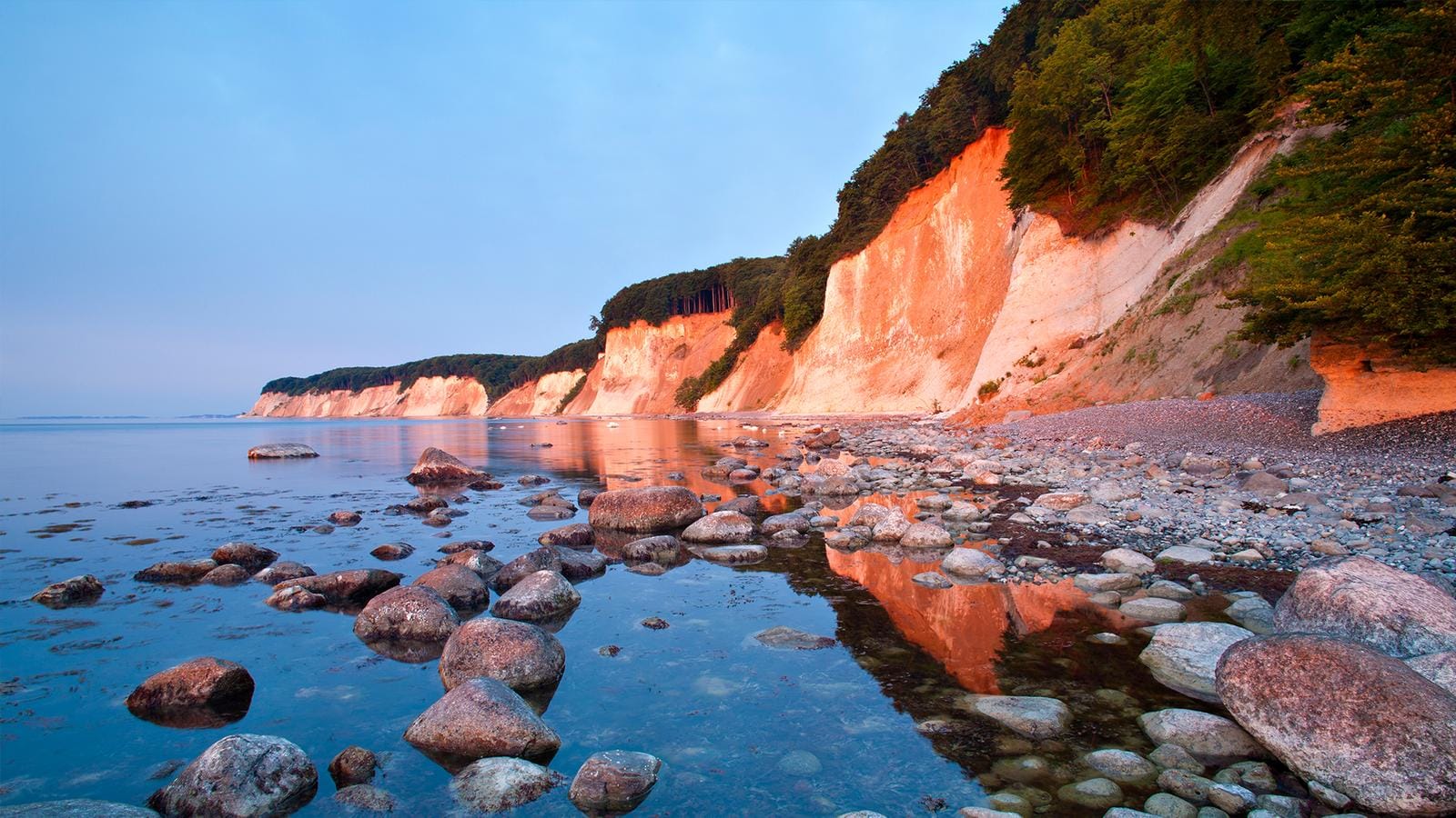 Steilküste und Meer auf Rügen, Deutschland. Malerische Felsen in warmem Licht am Wasser.