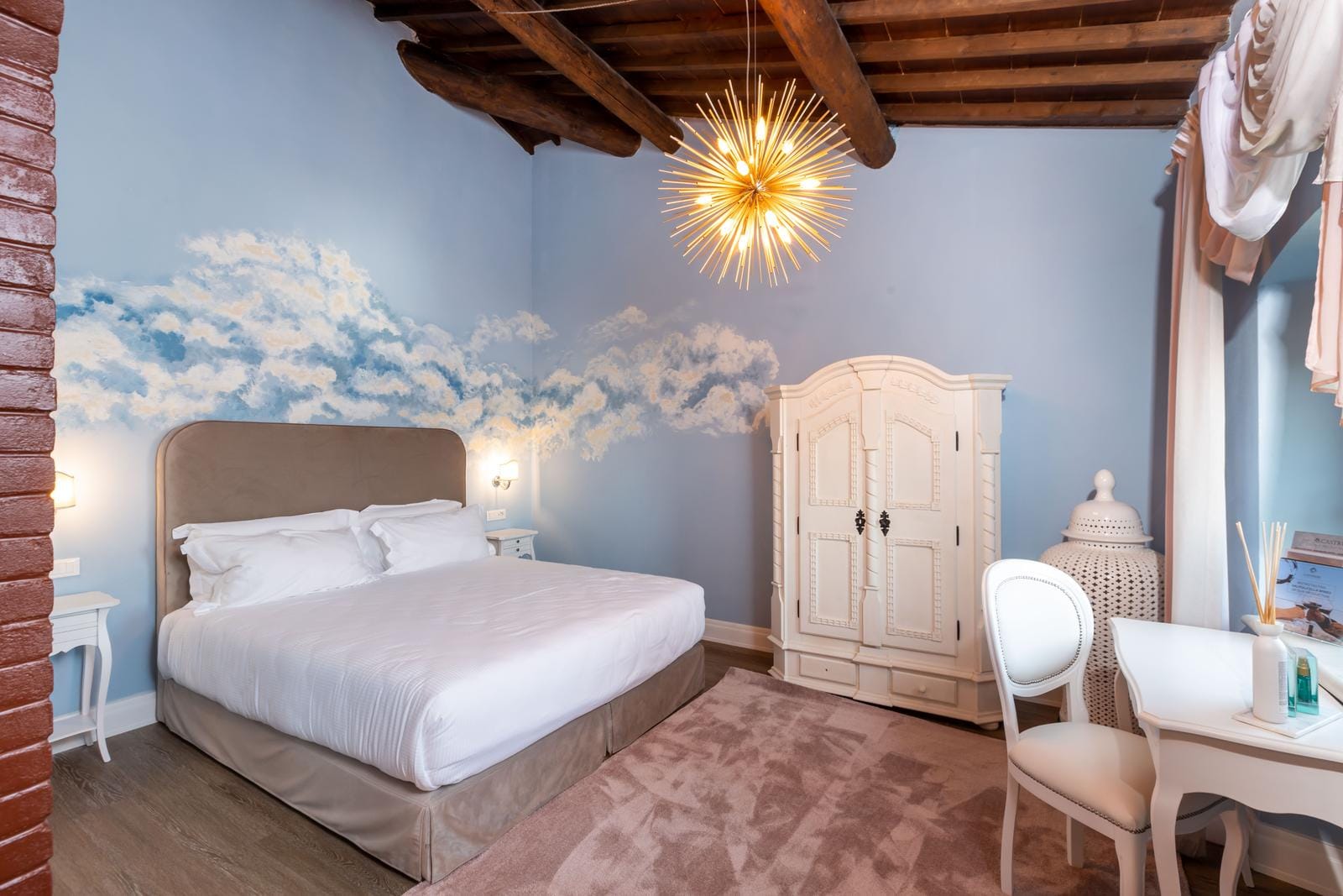 Elegantes Hotelzimmer mit Wandbemalung, Holzbalkendecke, Kronleuchter und Antikmöbeln.