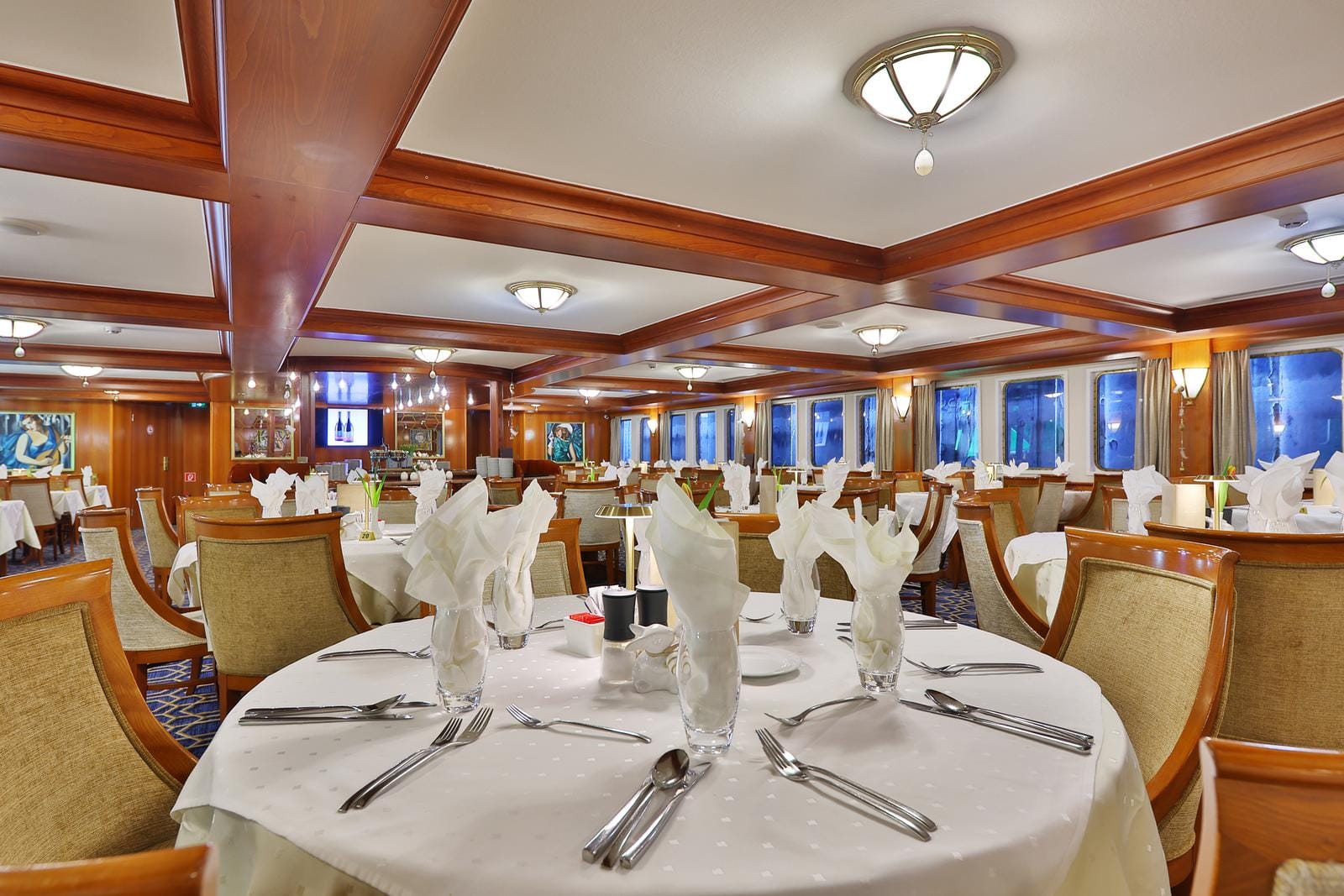 Elegantes Hotelrestaurant mit Holzausstattung, gedeckte Tische, gedämpfte Beleuchtung.