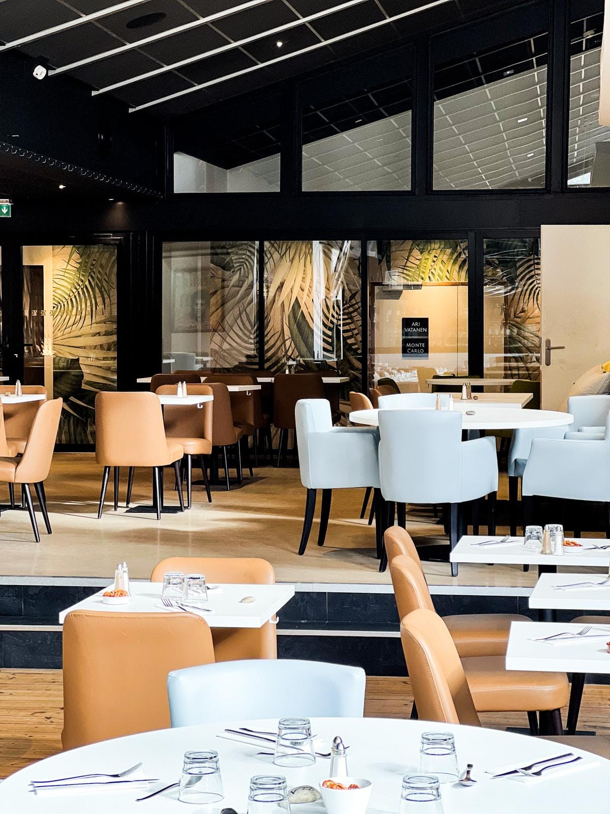Modernes Hotelrestaurant mit eleganten weißen und beigen Stühlen, botanische Wandmuster.