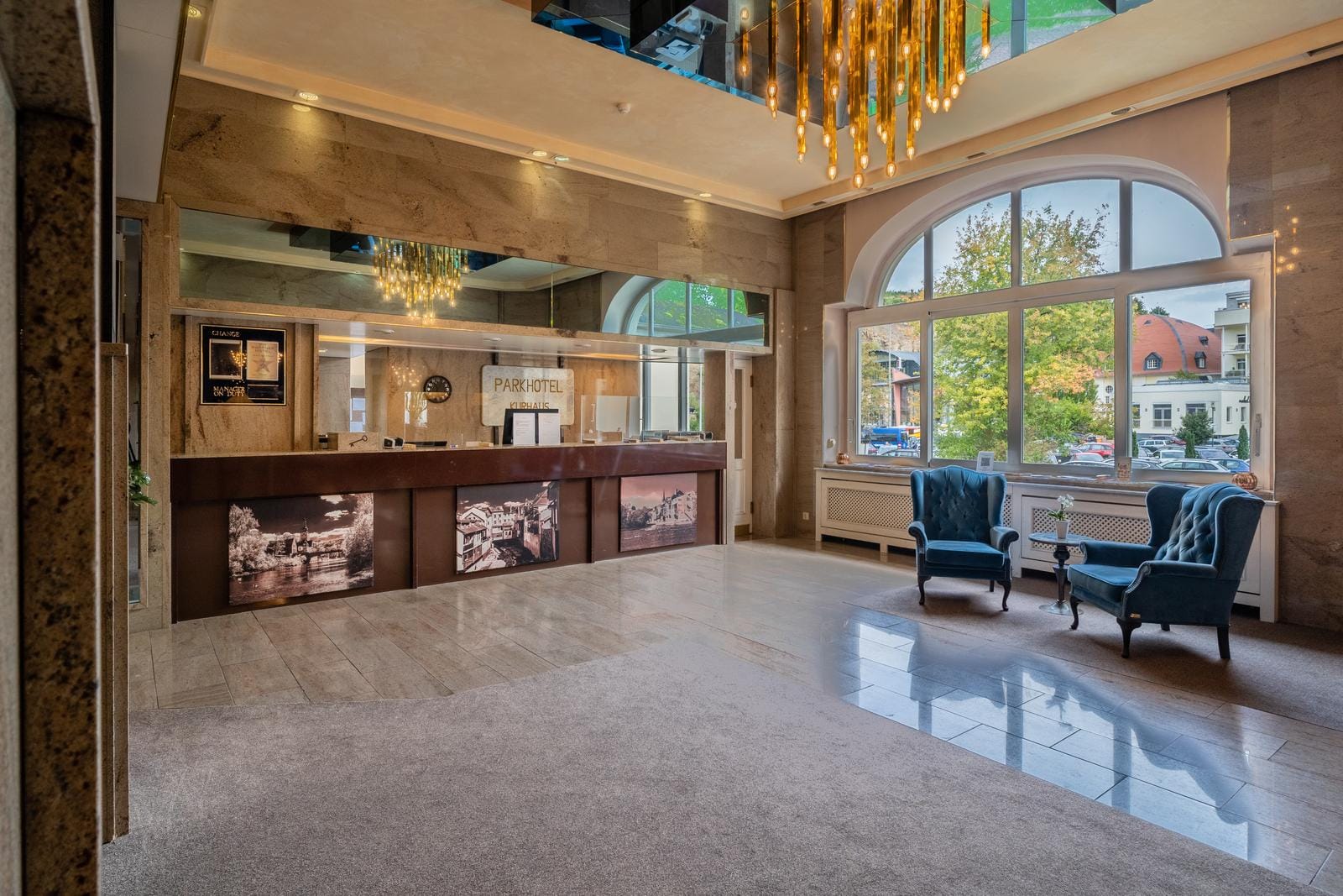 Helle Lobby mit blauen Sesseln, großer Fensterfront und elegantem Kronleuchter.