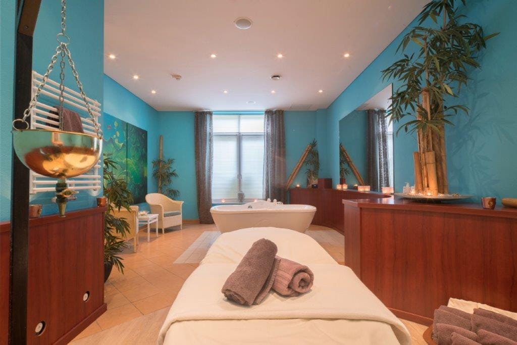 Elegantes Spa mit blauen Wänden, Bambusdekor und Massagebereich mit Badewanne.