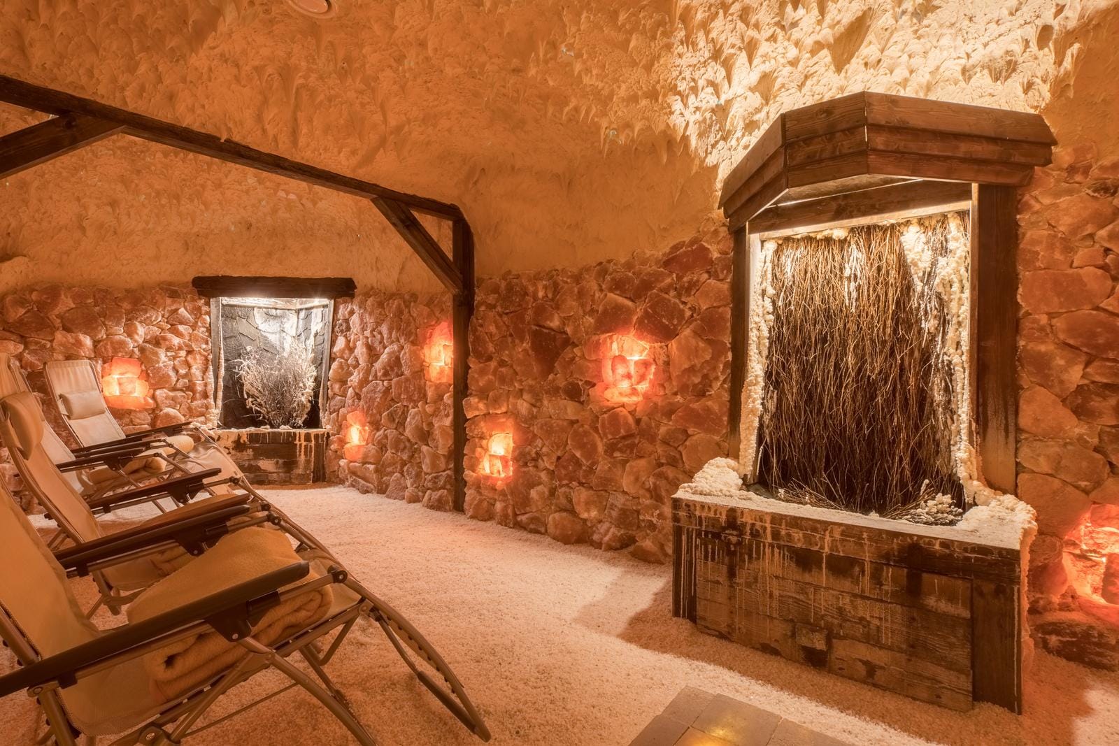 Salzgrotten-Spa mit Liegestühlen, warmes Licht, rustikale Steinwände und hölzerne Elemente.