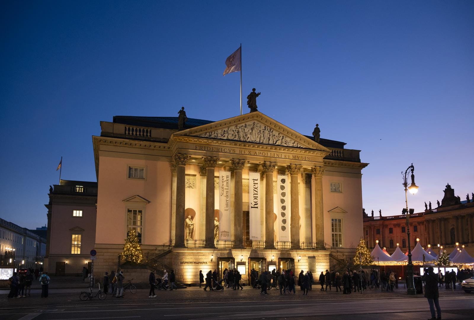 Opernhaus in Berlin bei Abenddämmerung, beleuchtet, mit Weihnachtsdekoration.