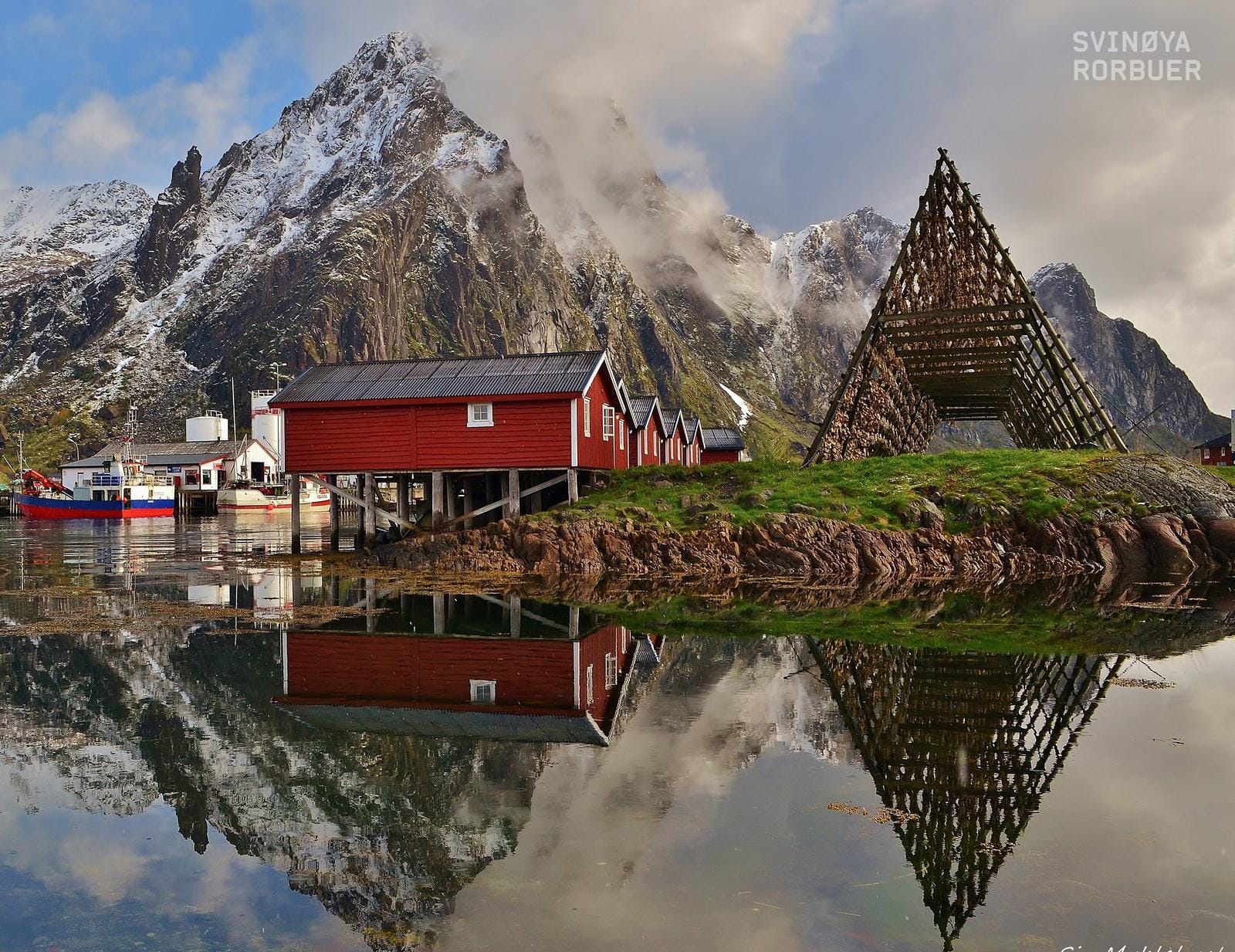 Rote Fischerhütten und Berge am Wasser in den Lofoten, Norwegen.