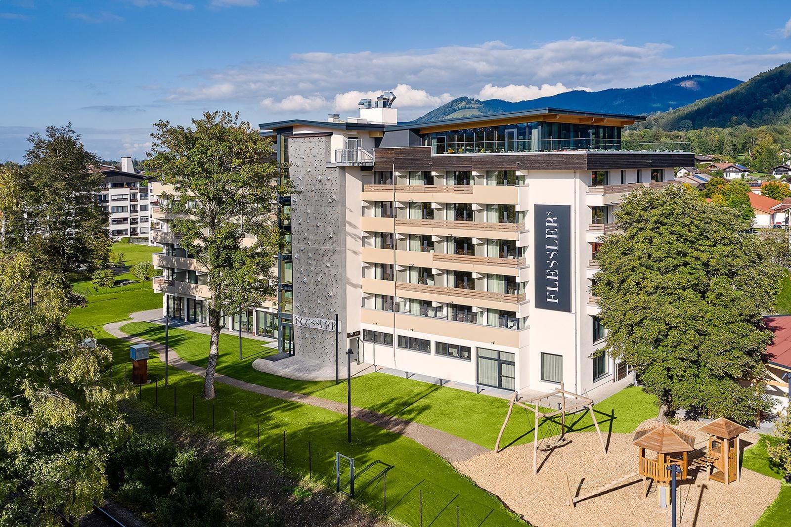 Modernes Hotel mit Kletterwand, großer Garten, Spielplatz und Bergblick.