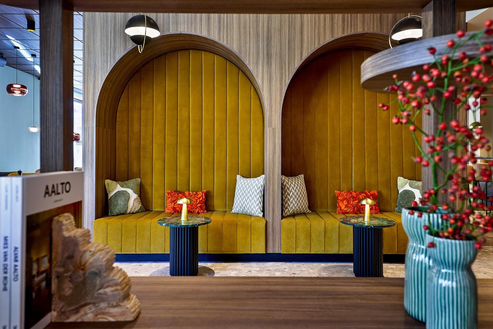 Moderne Hotel-Lounge mit gelben Nischen, bunten Kissen und stilvollen Lampen.