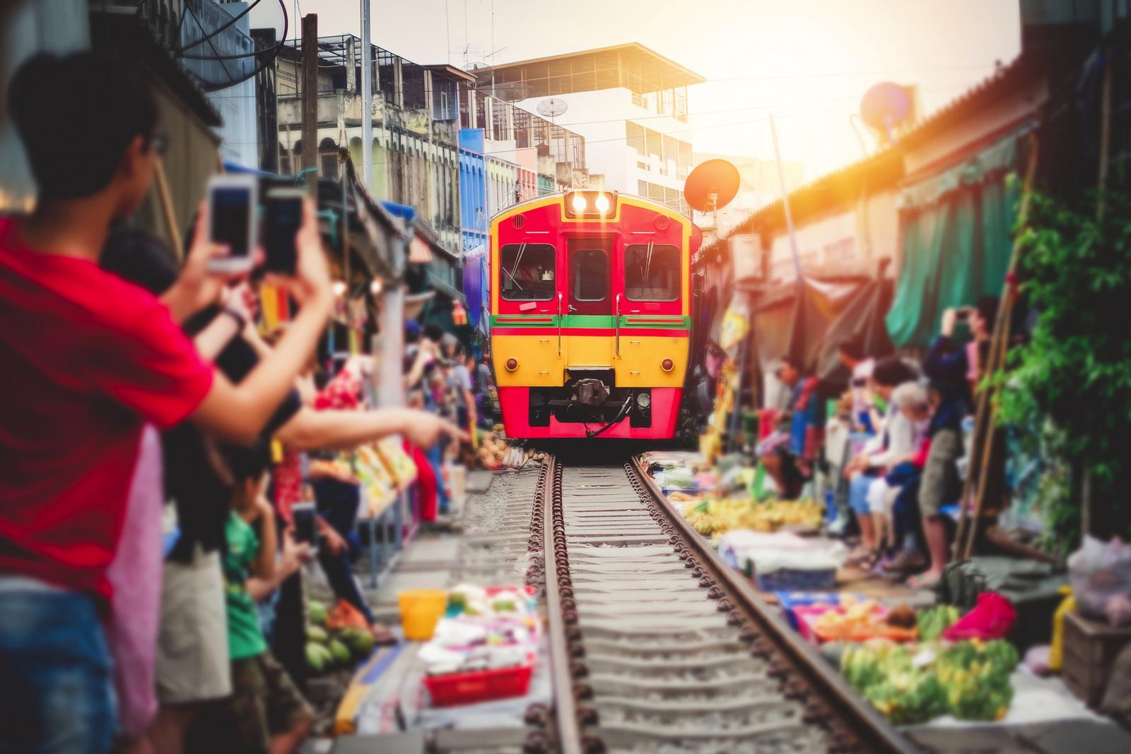 Bunte Bahn fährt durch den belebten Maeklong Railway Market in Thailand.