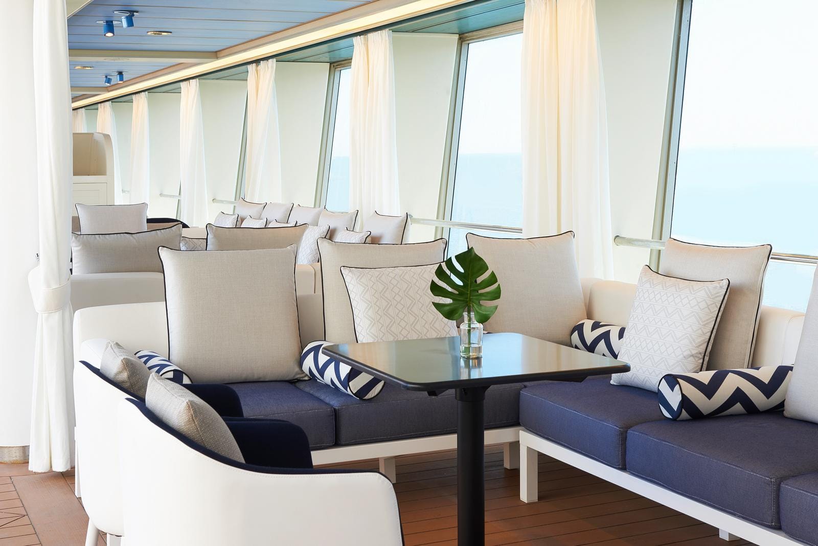 Moderner, maritim inspirierter Lounge-Bereich mit blauen Sofas und großer Fensterfront.