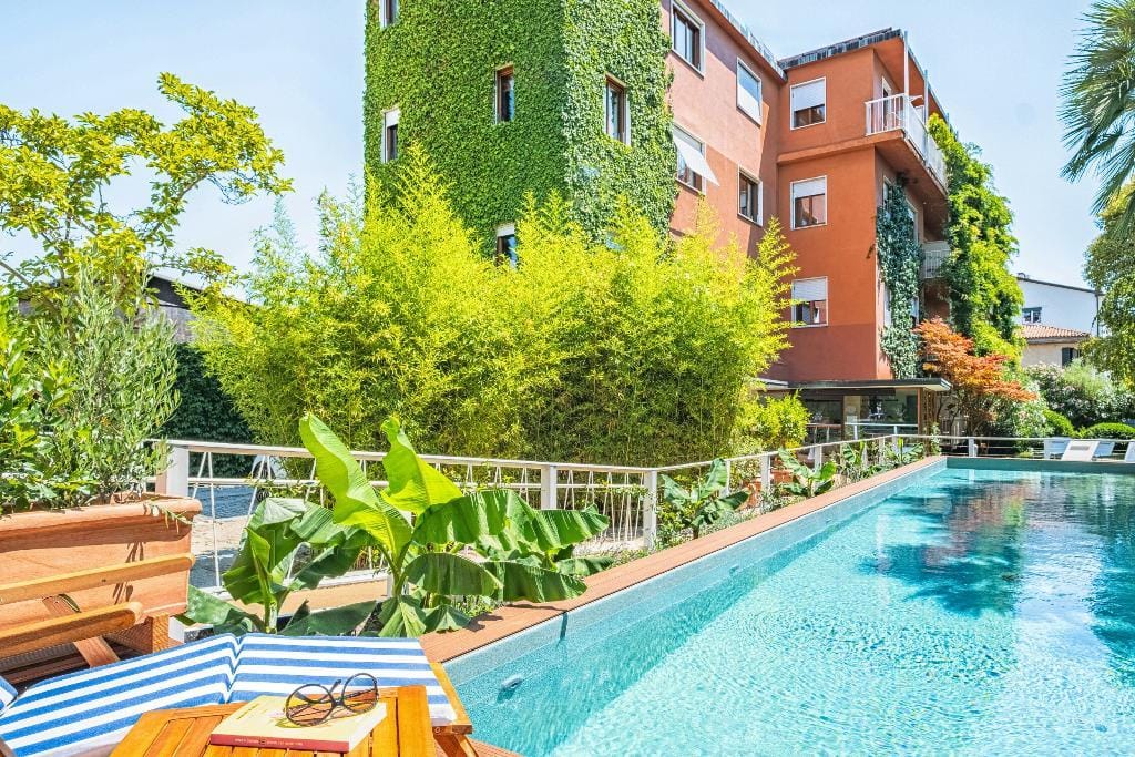 Hotel in mediterranem Stil mit grün bewachsener Fassade und modernem Pool im Garten.