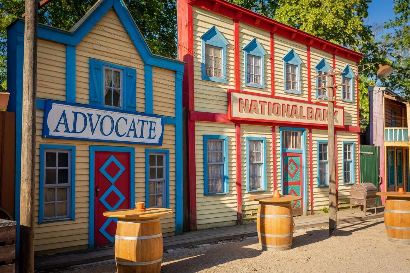 Bunte Western-Stadtkulisse mit "Nationalbank" und "Advocate" Schildern.