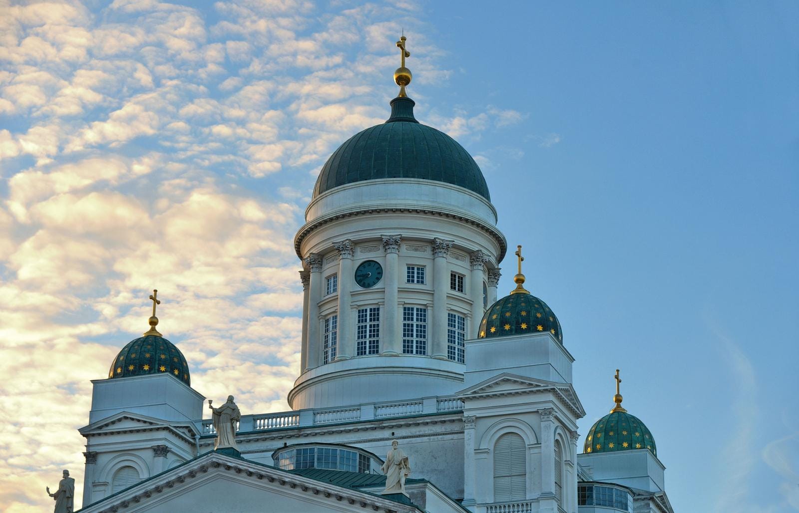 Helsinki, Finnland: Der weiße Dom mit grünen Kuppeln vor einem blau-weißen Himmel.