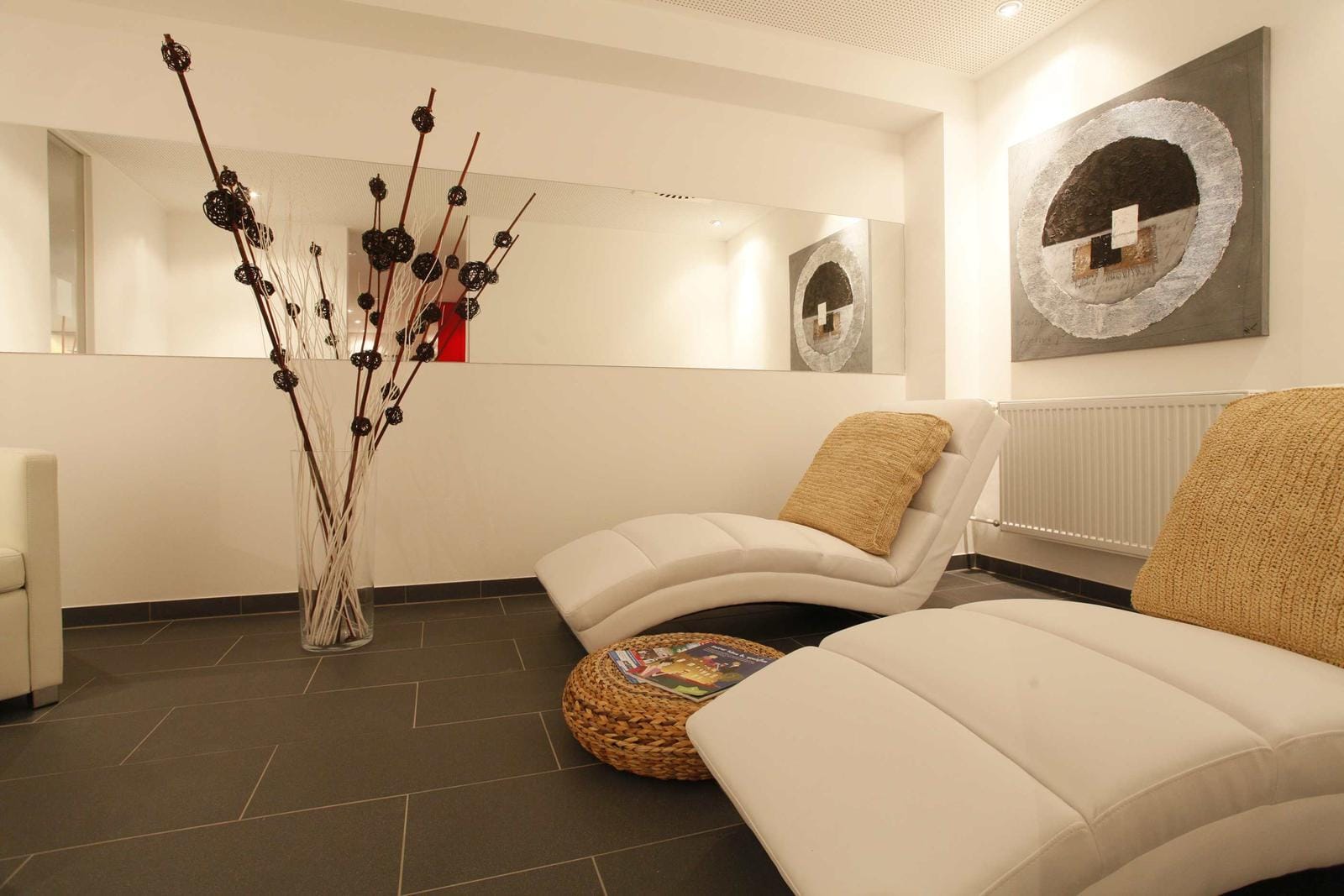Modernes Spa mit weißen Liegen, Kunstwerk, heller Atmosphäre und stilvollen Dekorationen.