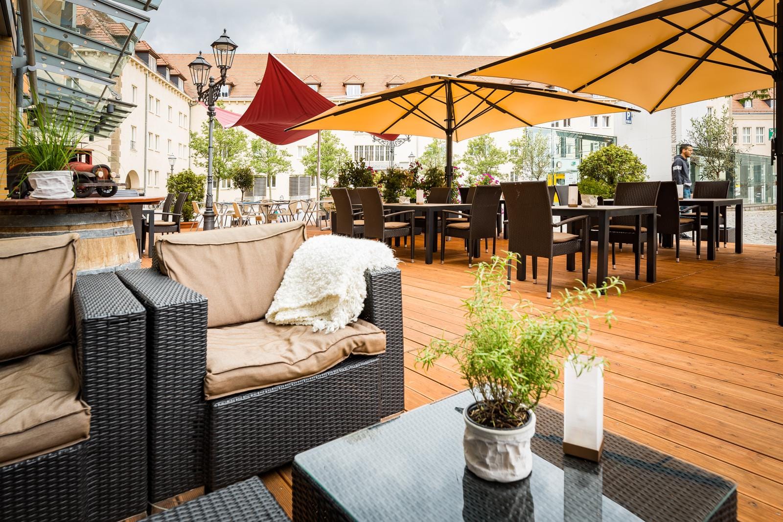 Gemütliche Hotelterrasse mit Rattanmöbeln, bunten Sonnenschirmen und Holzboden.