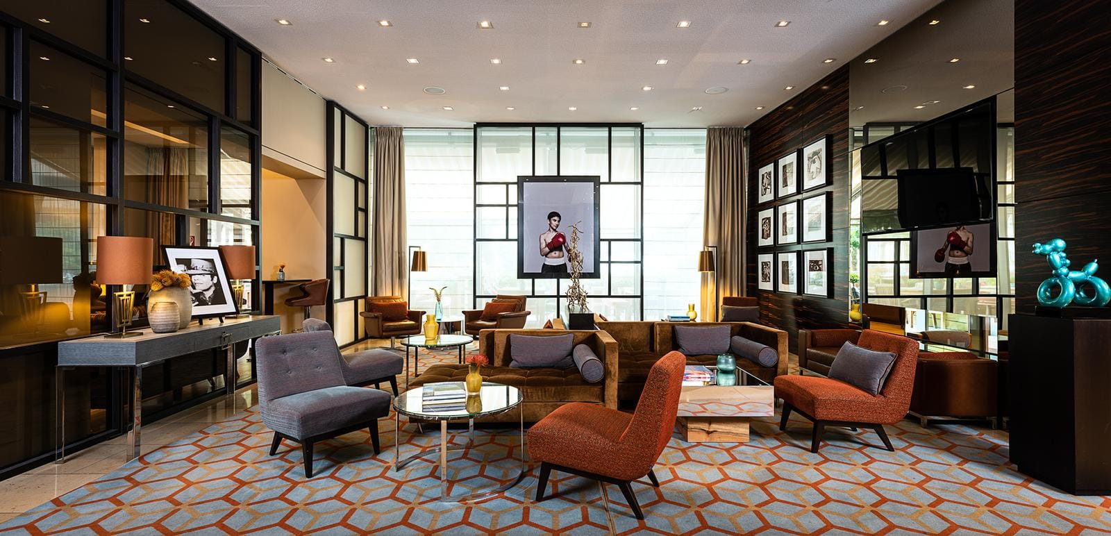 Moderne Hotel-Lobby mit stilvollen Sesseln, Kunstwerken und warmem Licht.