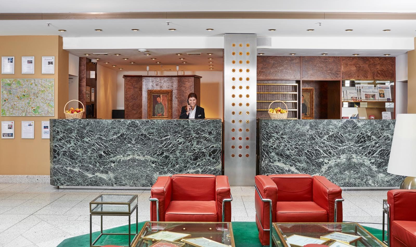 Hotel-Lobby mit grünem Marmortresen, roten Ledersesseln und moderner Dekoration.