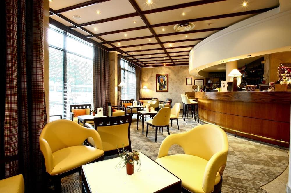 Gemütliche Hotelbar mit gelben Sesseln, Holztresen und warmem Licht.