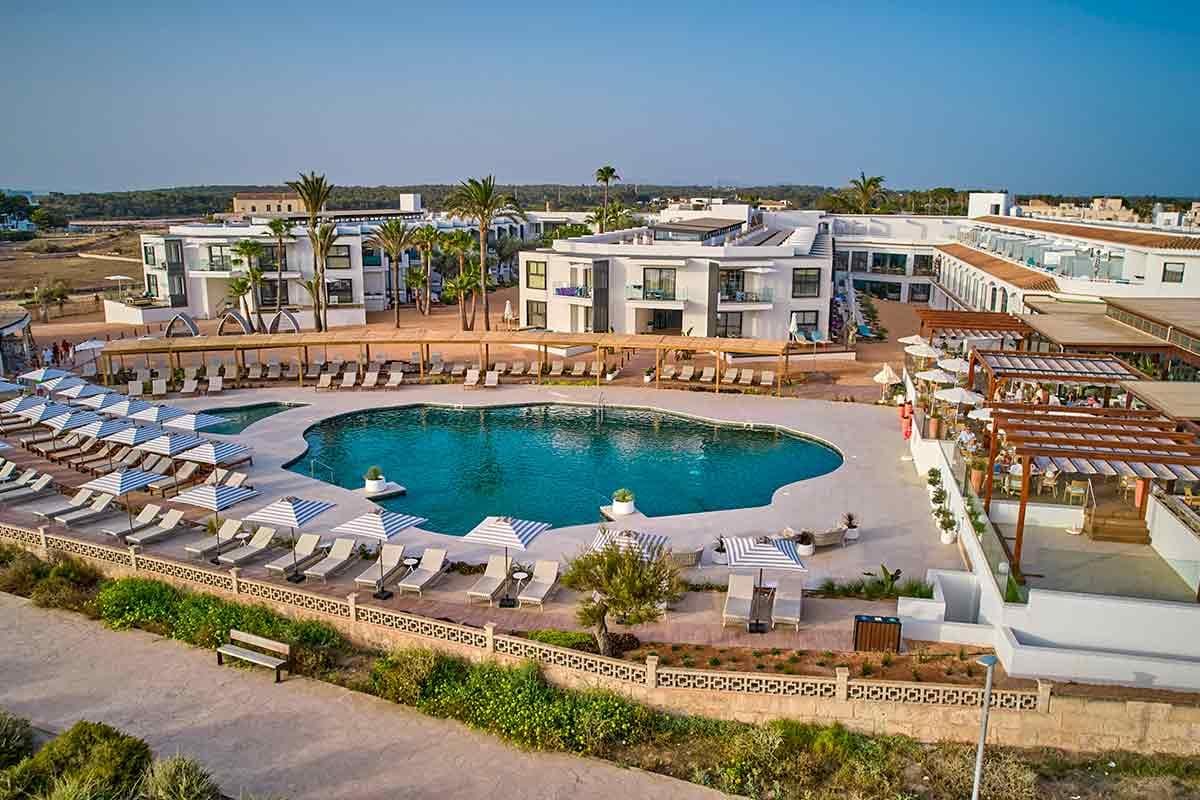 Luxushotel mit großem Pool, Liegestühlen und modernen weißen Gebäuden im mediterranen Stil.