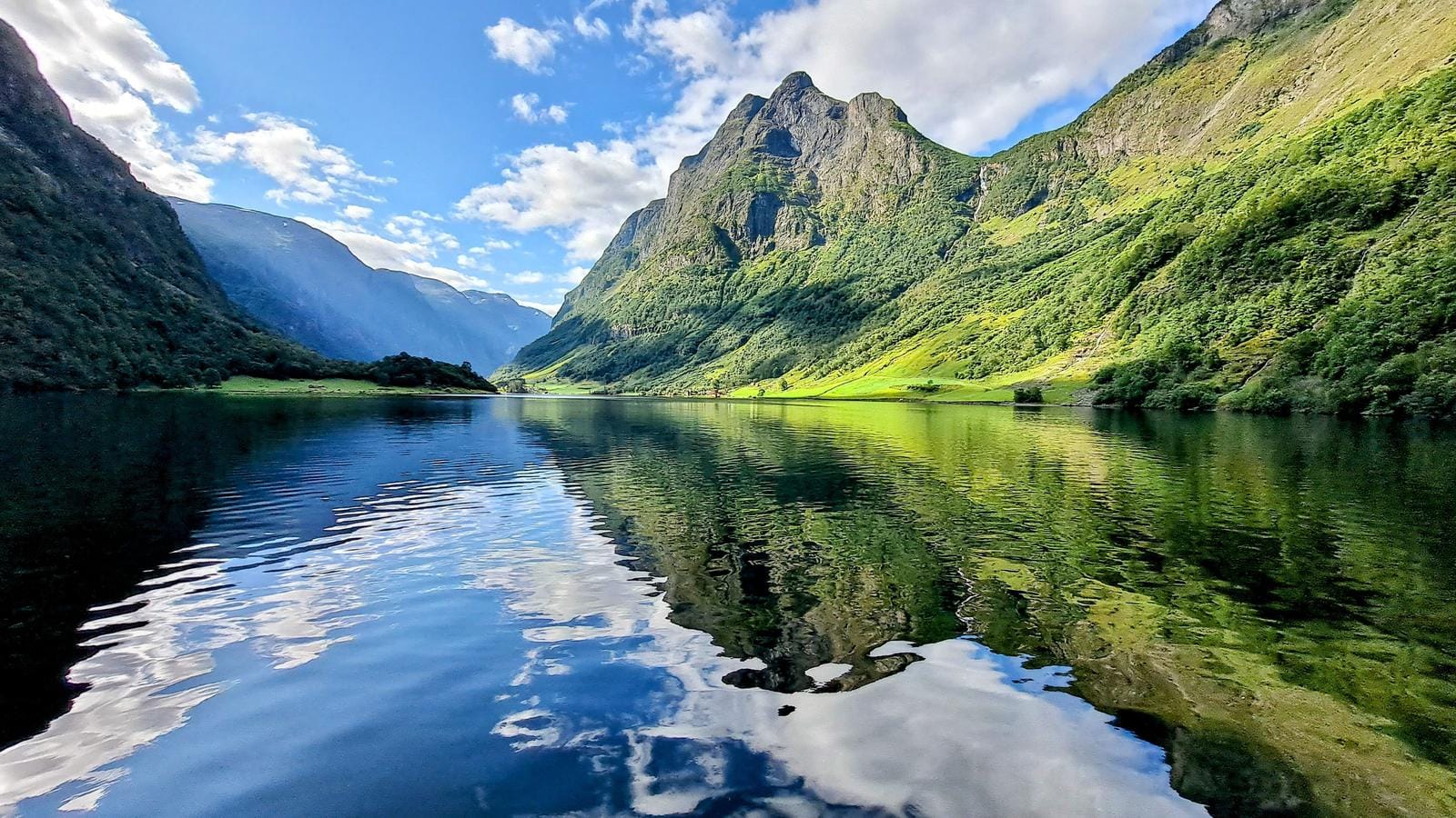 Fjordlandschaft in Norwegen, Berge spiegeln sich idyllisch im klaren Wasser bei Sonnenlicht.