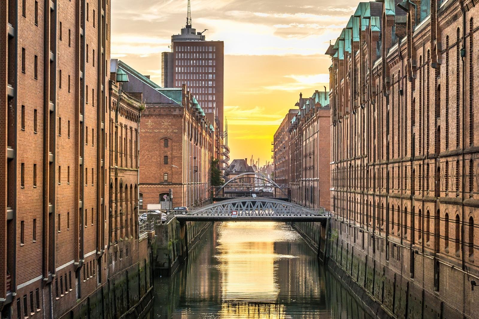Sonnenuntergang beleuchtet historische Backsteinbauten an einem Kanal in Hamburg, Deutschland.