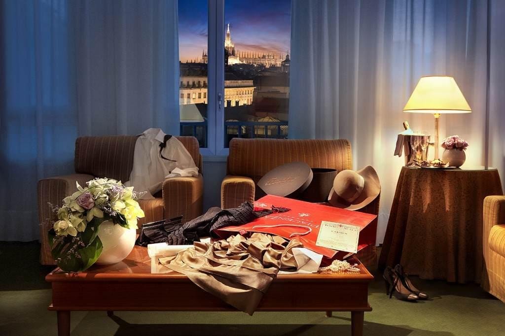 Elegantes Hotelzimmer mit Blumenvase, Abendkleidung und Stadtblick bei Dämmerung.