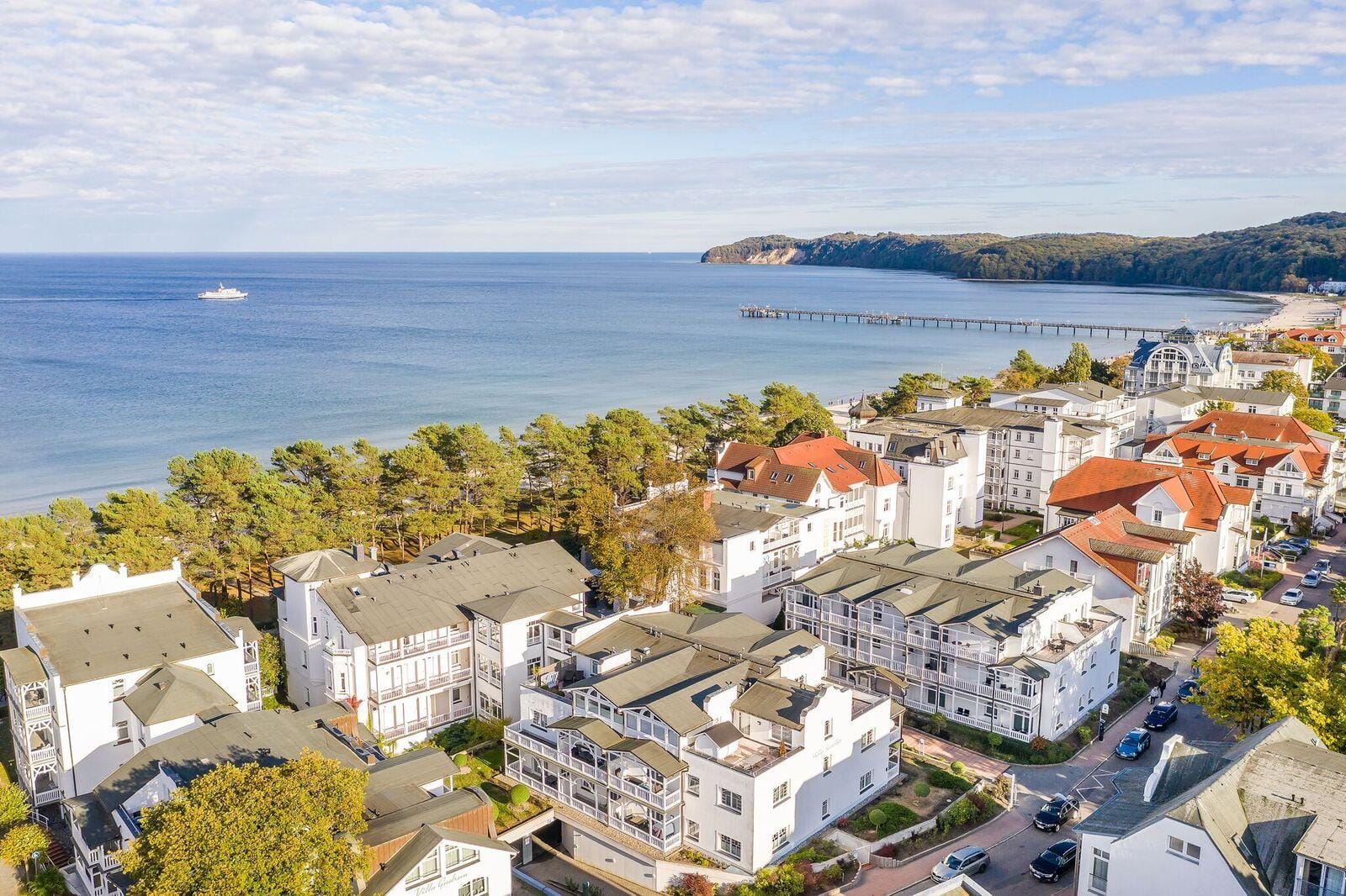 Luftaufnahme von Binz, Rügen mit Küste, Hotels und Pier, blauem Himmel und Meer.