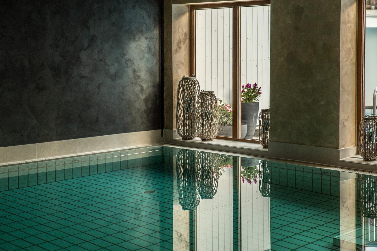 Eleganter Innenpool mit grünen Fliesen, dekorativen Laternen und Fensterblick.