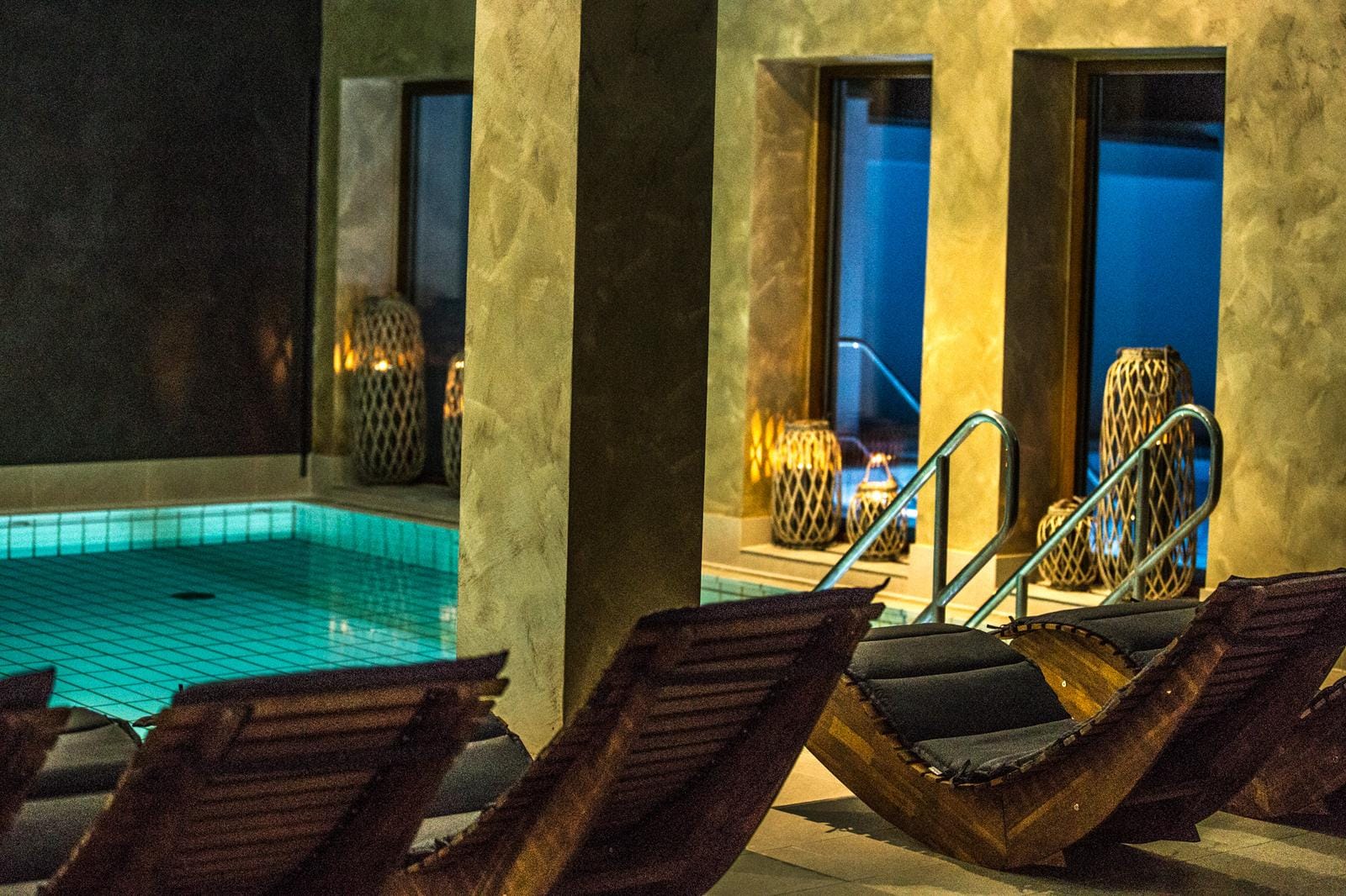 Elegantes Hotel-Spa mit Innenpool, Holzliegen und gedämpfter Beleuchtung.
