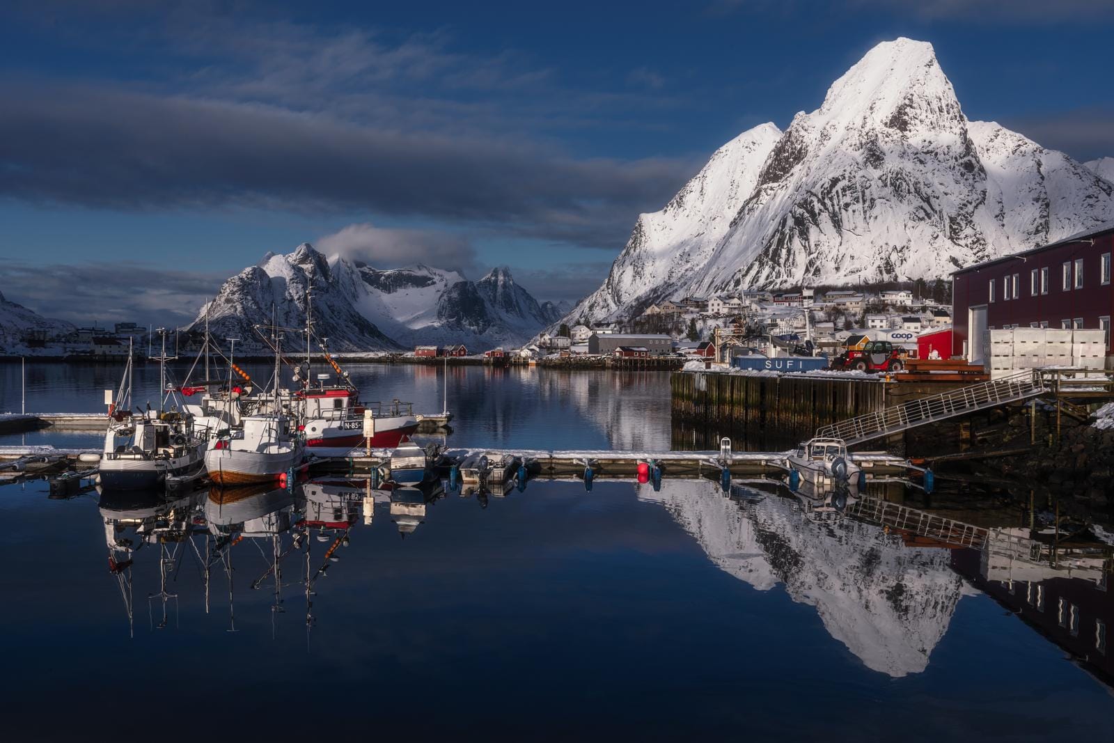 Verschneite Berge und ruhiger Hafen mit Booten in Reine, Lofoten, Norwegen. Atemberaubend!