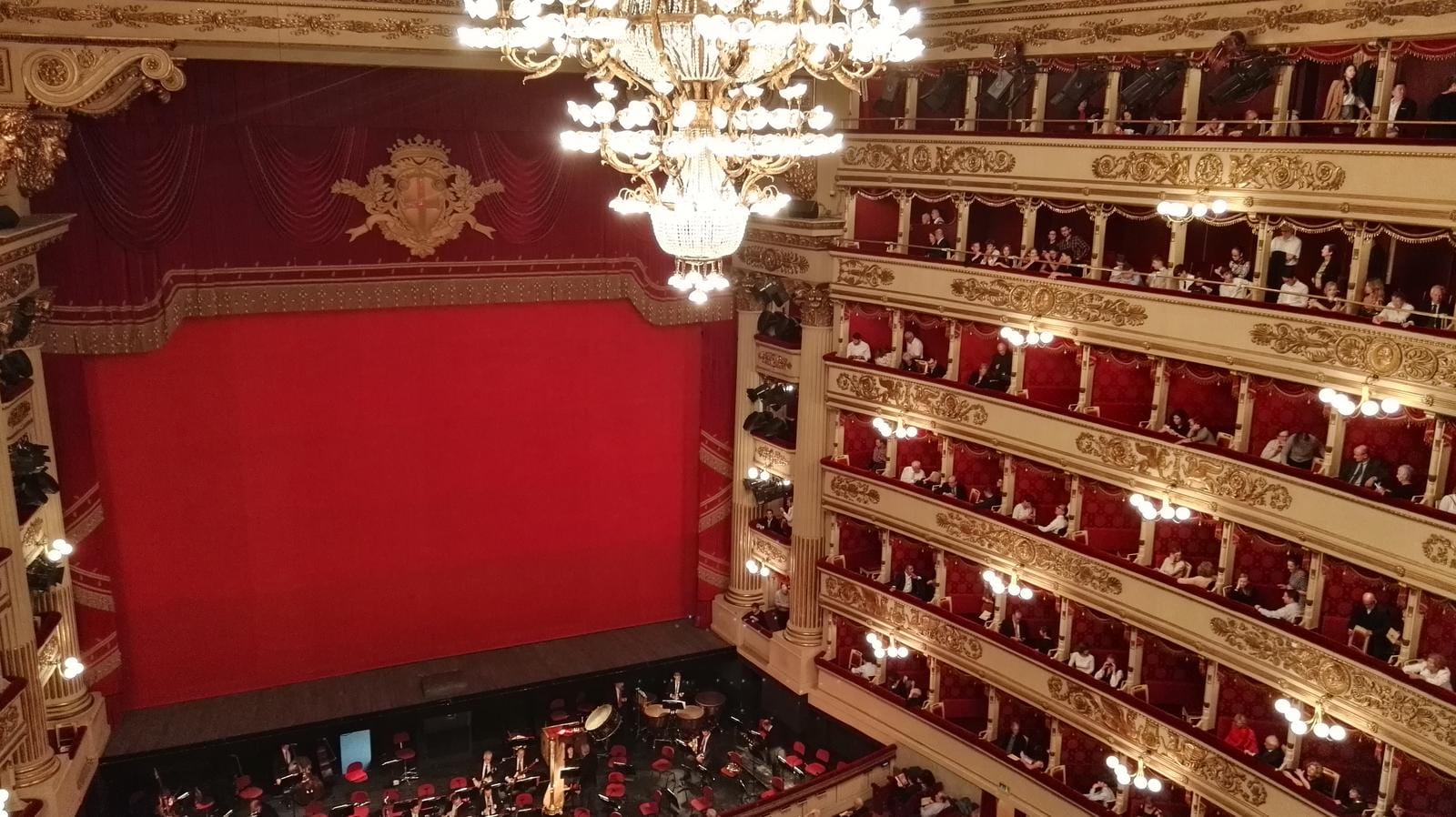 Prunkvoller Opernsaal mit rotem Vorhang und verzierten goldenen Balkonen.
