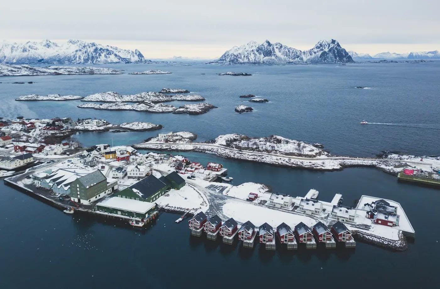 Winterliches Fischerdorf auf den Lofoten, Norwegen, mit verschneiten Häusern und Fjord.
