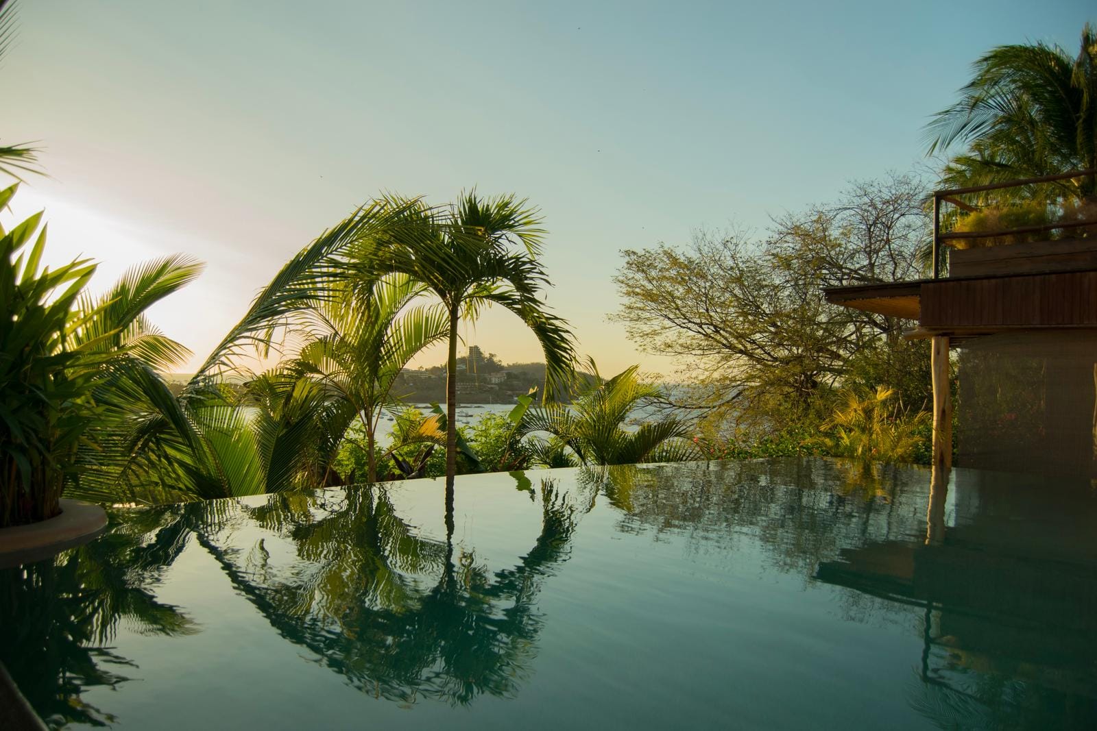 Infinity-Pool mit Palmenblick, tropisches Ambiente bei Sonnenuntergang in Küstenregion.