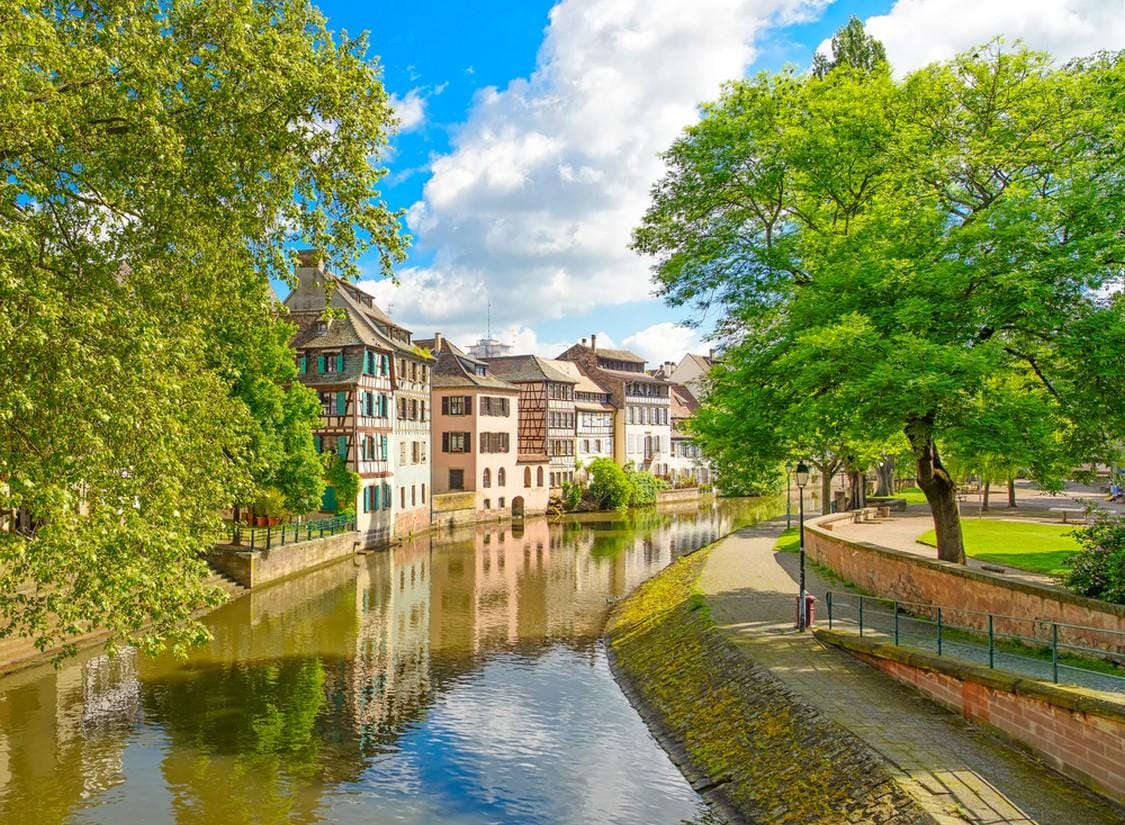 Fachwerkhäuser am Flussufer in Straßburg, Frankreich, bei sonnigem Wetter.
