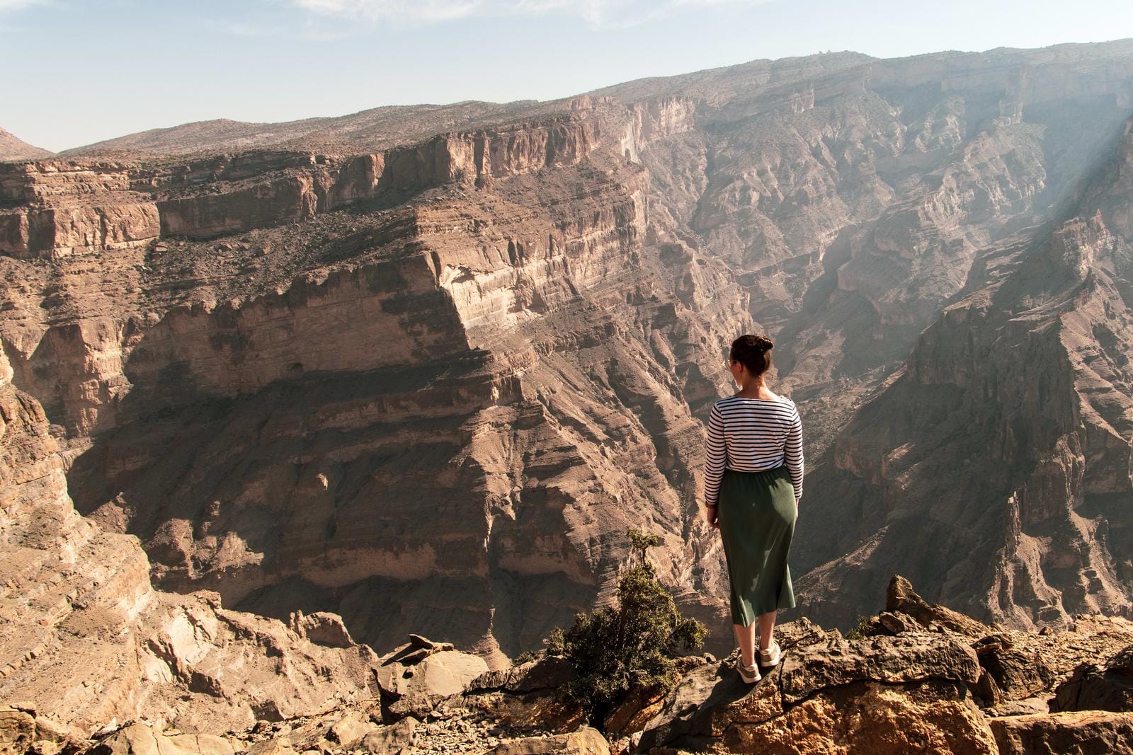 Frau steht am Rand des Grand Canyons in Oman, umgeben von majestätischen Felslandschaften.