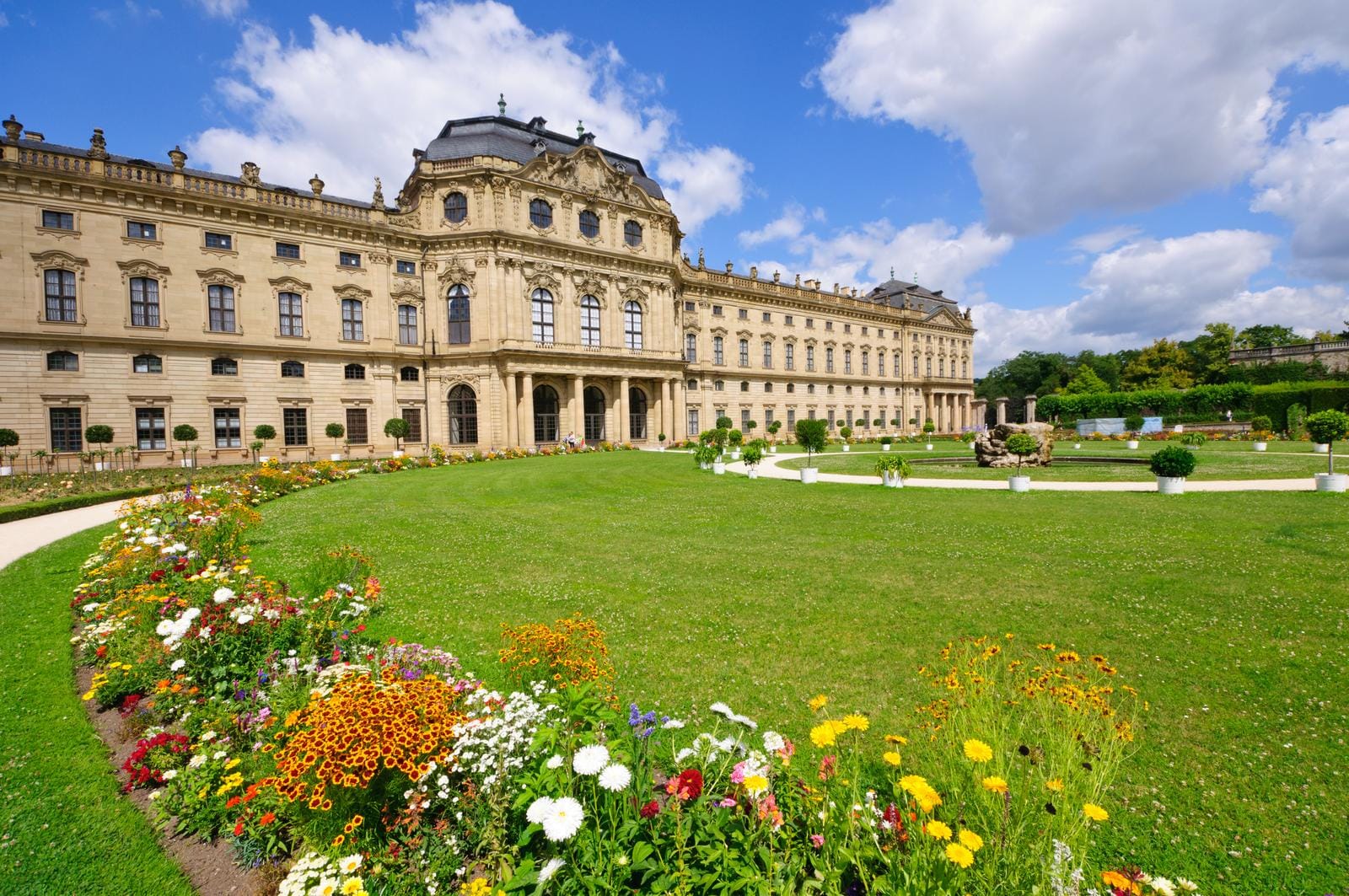 Barocker Palast mit prächtigem Garten in Würzburg, Deutschland bei blauem Himmel.