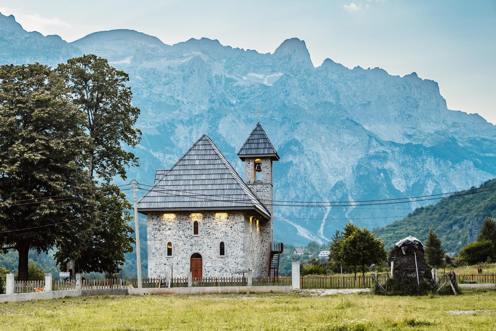 Steinkapelle im Grünen vor eindrucksvoller Bergkulisse in Thethi, Albanien.