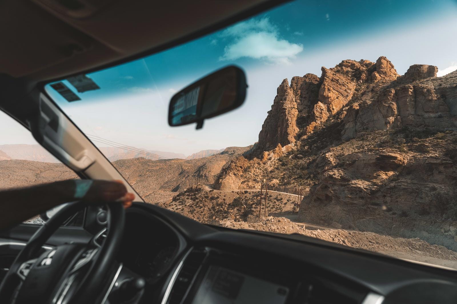 Blick aus dem Auto auf felsige Wüste und klare, blaue Himmel.