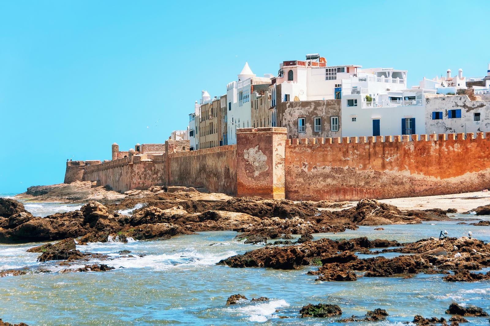 Küstenstadt Essaouira, Marokko, mit historischer Mauer, blauem Himmel und Ozean.