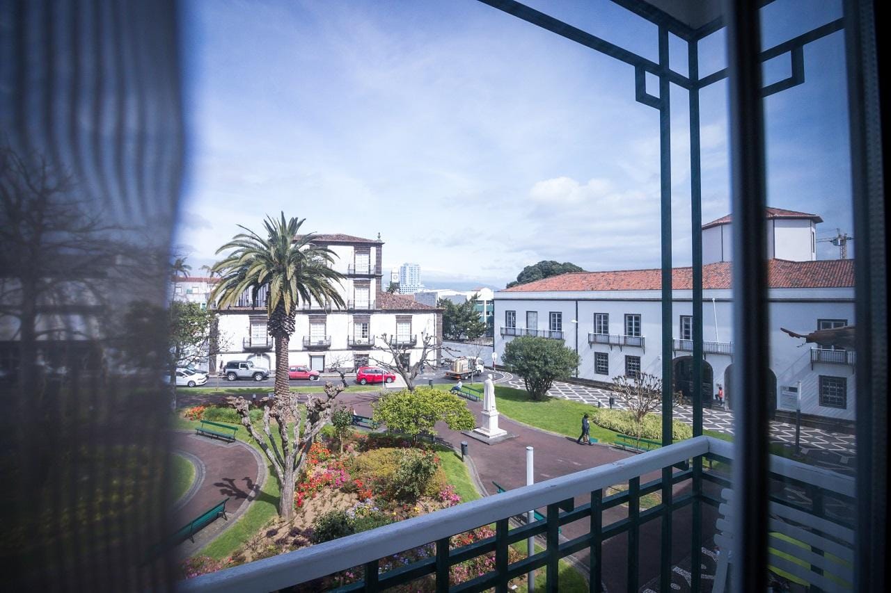 Blick auf grünen Garten mit Palmen und weißen Gebäuden in Funchal, Portugal.