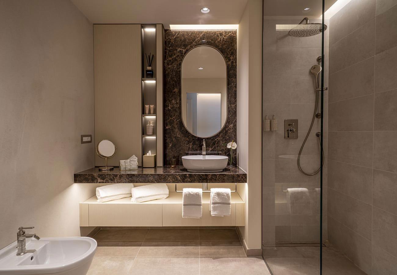 Elegantes Hotelbad mit modernem Waschtisch, Regendusche und stimmungsvollem Licht.