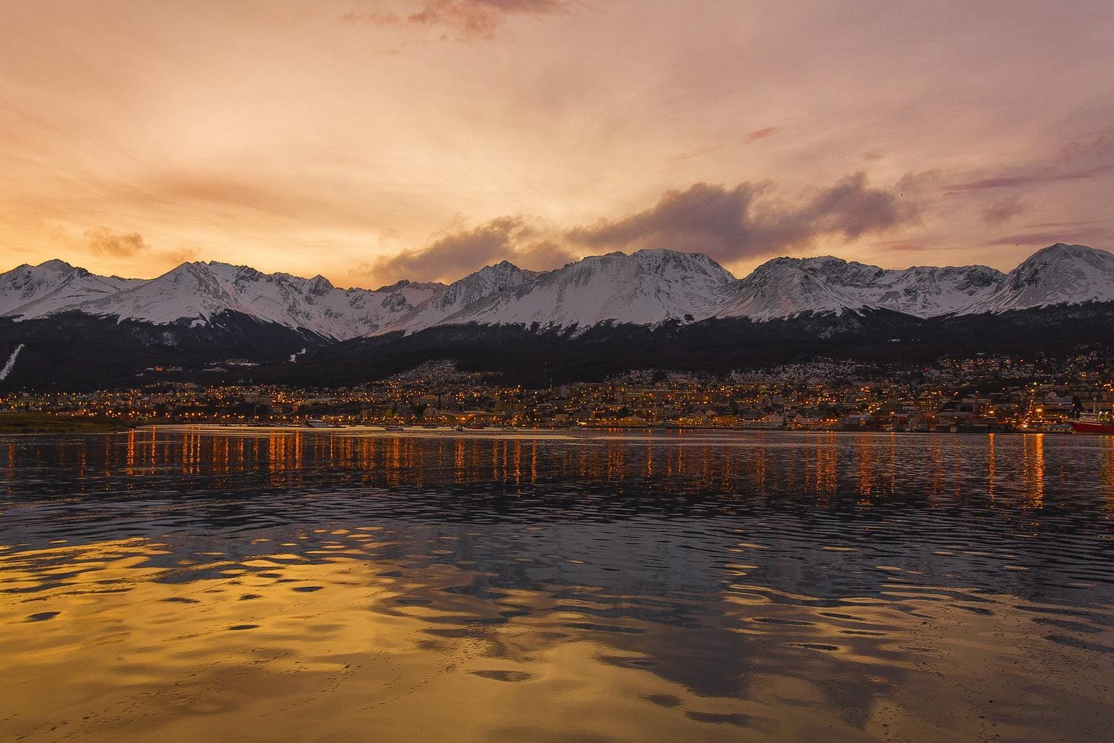 Stadtansicht von Ushuaia in Argentinien bei Sonnenuntergang mit schneebedeckten Bergen.