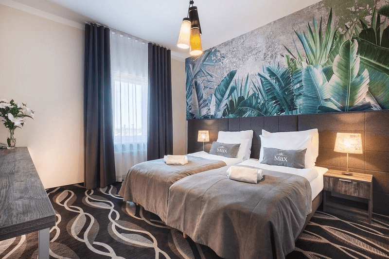 Modernes Hotelzimmer mit zwei Betten, Dschungelmotiv-Wand und elegantem Teppich.