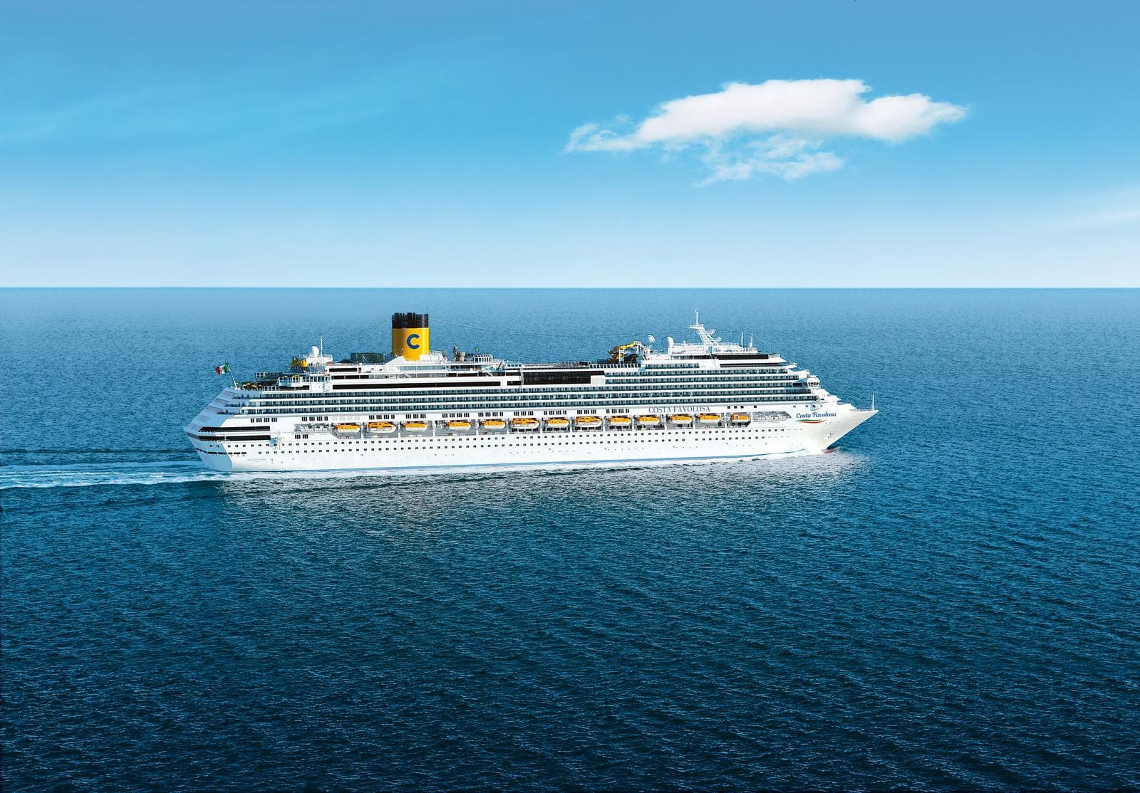 Kreuzfahrtschiff fährt bei sonnigem Wetter auf blauem Meer, blauer Himmel im Hintergrund.