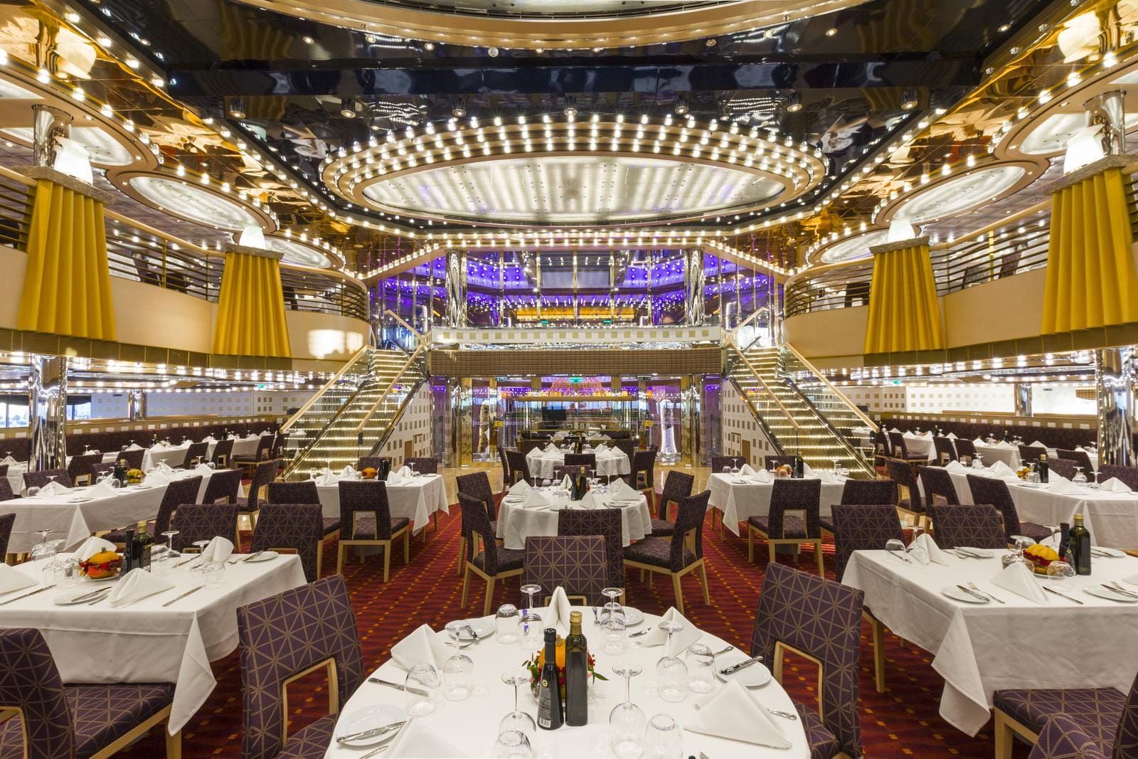 Elegantes Restaurant mit opulentem Kronleuchter, weißen Tischdecken und luxuriösem Ambiente.