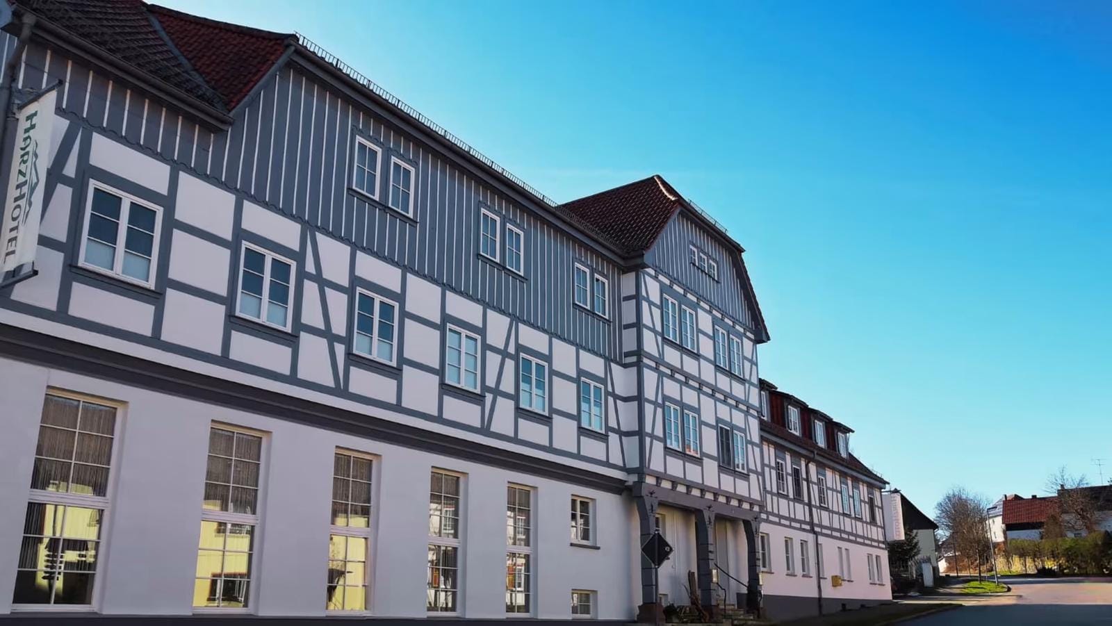 Hotel mit Fachwerkfassade und roten Dächern unter blauem Himmel.