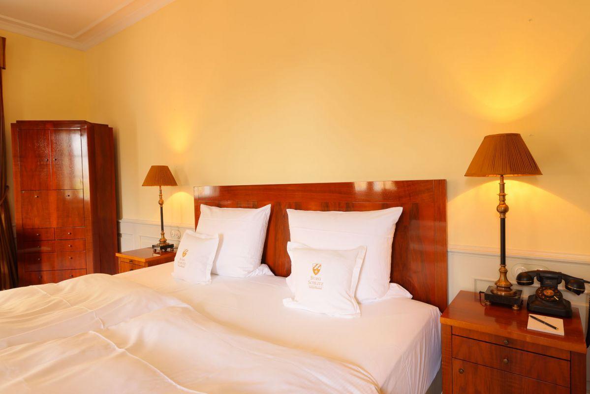 Klassisches Hotelzimmer mit Holzmöbeln, beigem Anstrich und warmem Licht.