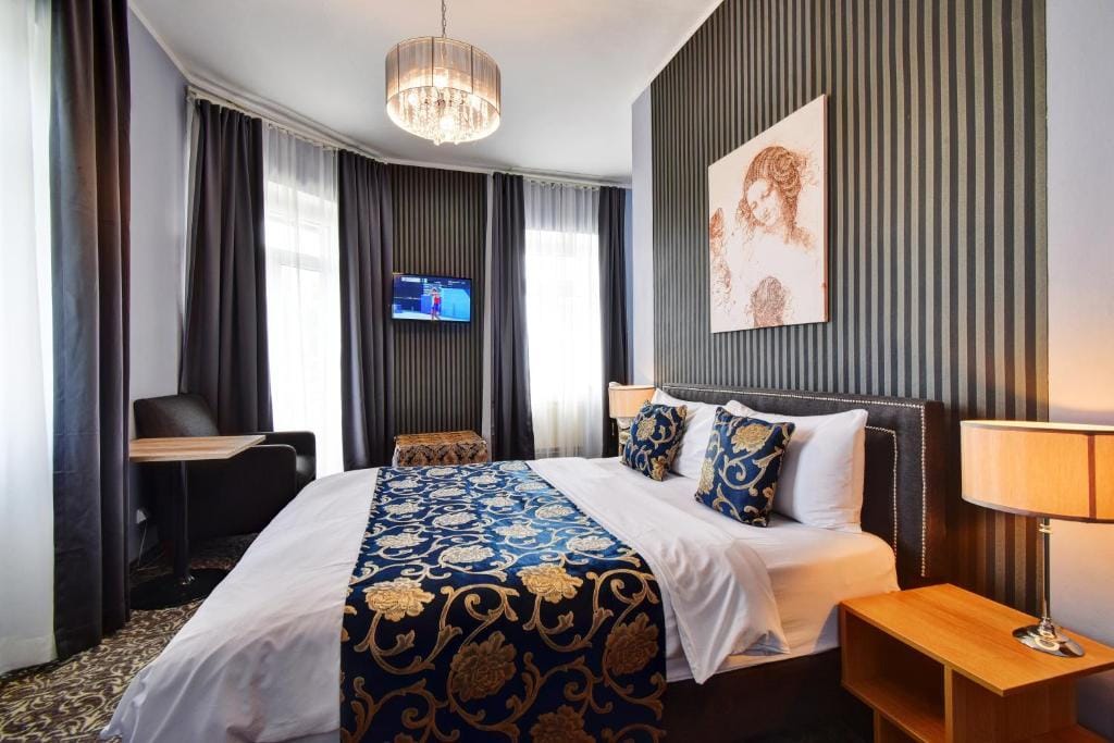 Luxuriöses Hotelzimmer mit Doppelbett, eleganter Tapete und Kronleuchter.