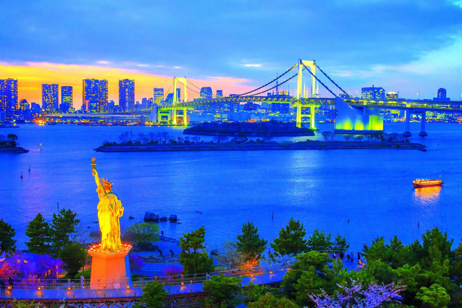 Abendblick auf Tokios Regenbogenbrücke und Freiheitsstatue vor beleuchteter Skyline.