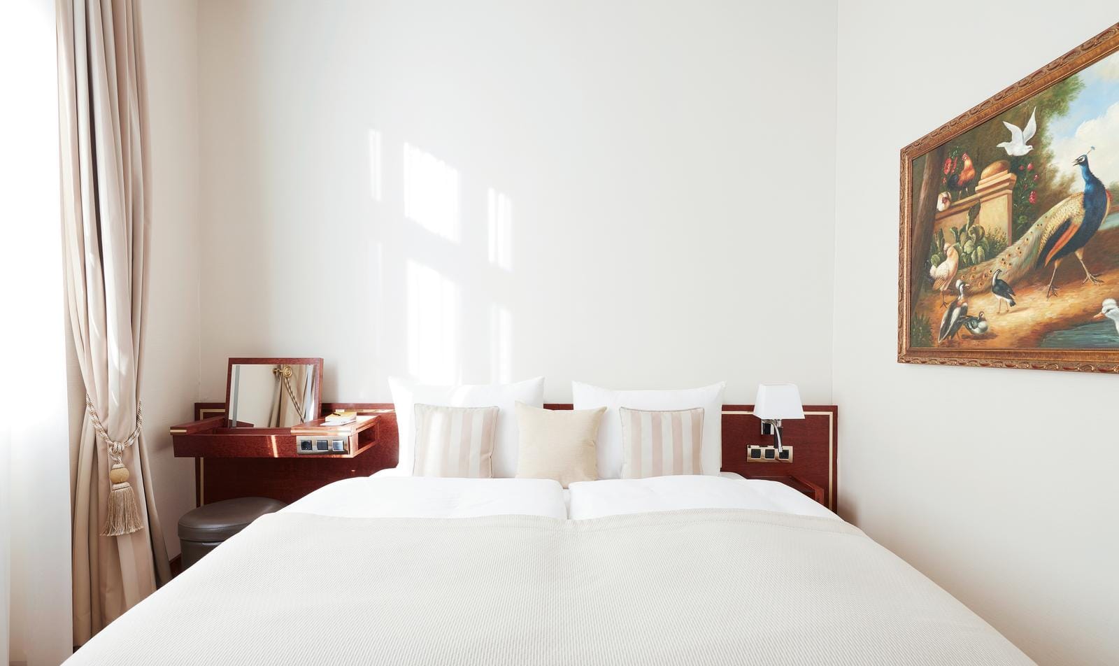 Helles Hotelzimmer mit Doppelbett, klassischem Gemälde und eleganter Einrichtung.