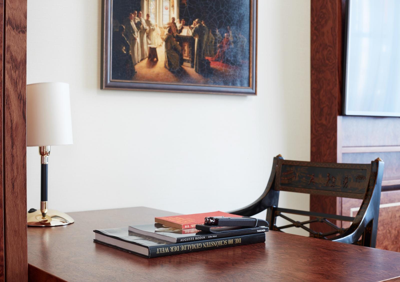 Eleganter Schreibtisch mit Kunststuhl, Lampe und Büchern, gemütliches Ambiente.